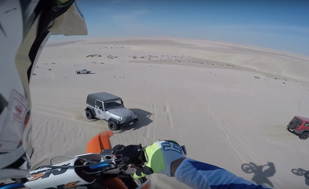 Un vélo tout-terrain saute de 100 pieds avant d'atterrir sur une Jeep dans le désert