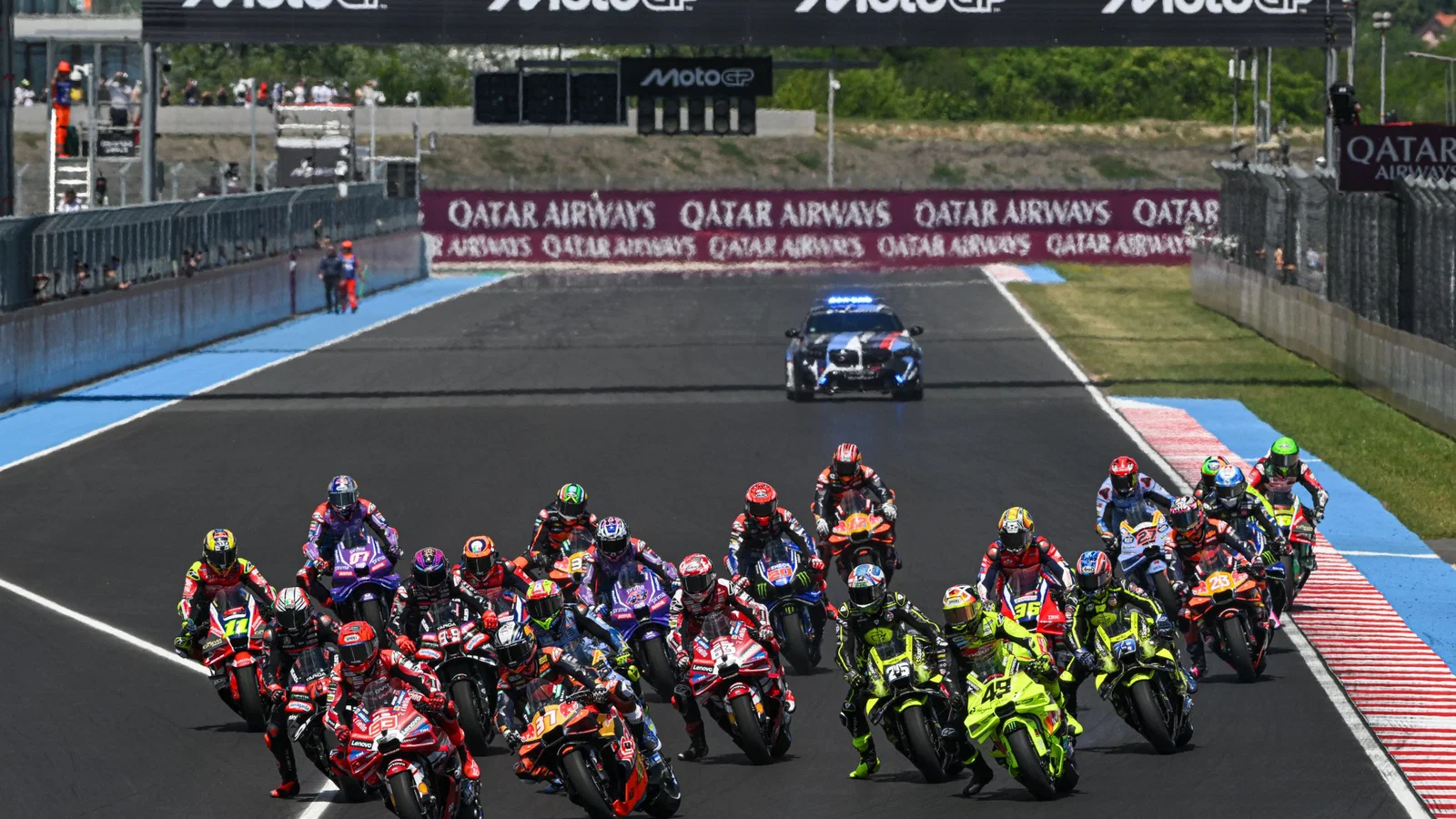 A grid of MotoGP bikes heading into a turn