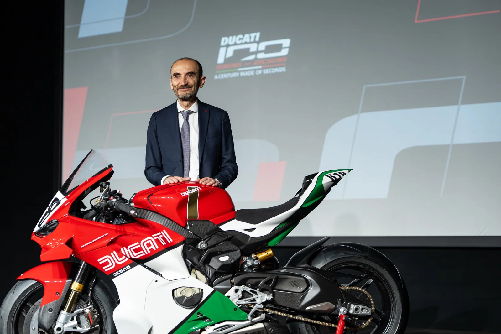 Claudio Domenicali debout avec une moto Ducati.